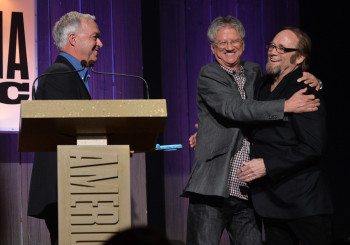 Richie Furay hugs Stephen Stills while Ken Paulson looks on at the 2013 Americana Music Association Honors and Awards show.